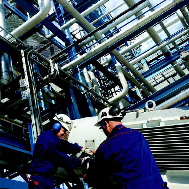 Two men with hard hats and ear protection working on construction site