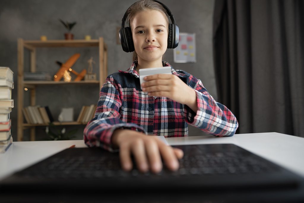 Young girl wearing gamin headset and typing in credit card information on computer
