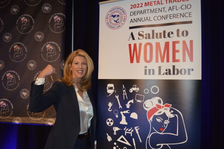 Bridget Martin doing flexing pose next to A Salute to Women in Labor