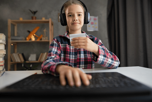 Young girl wearing gamin headset and typing in credit card information on computer