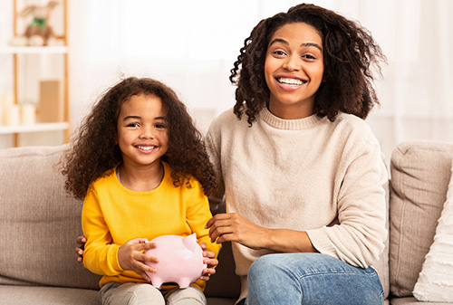 Mom and daughter smiling with piggy bank